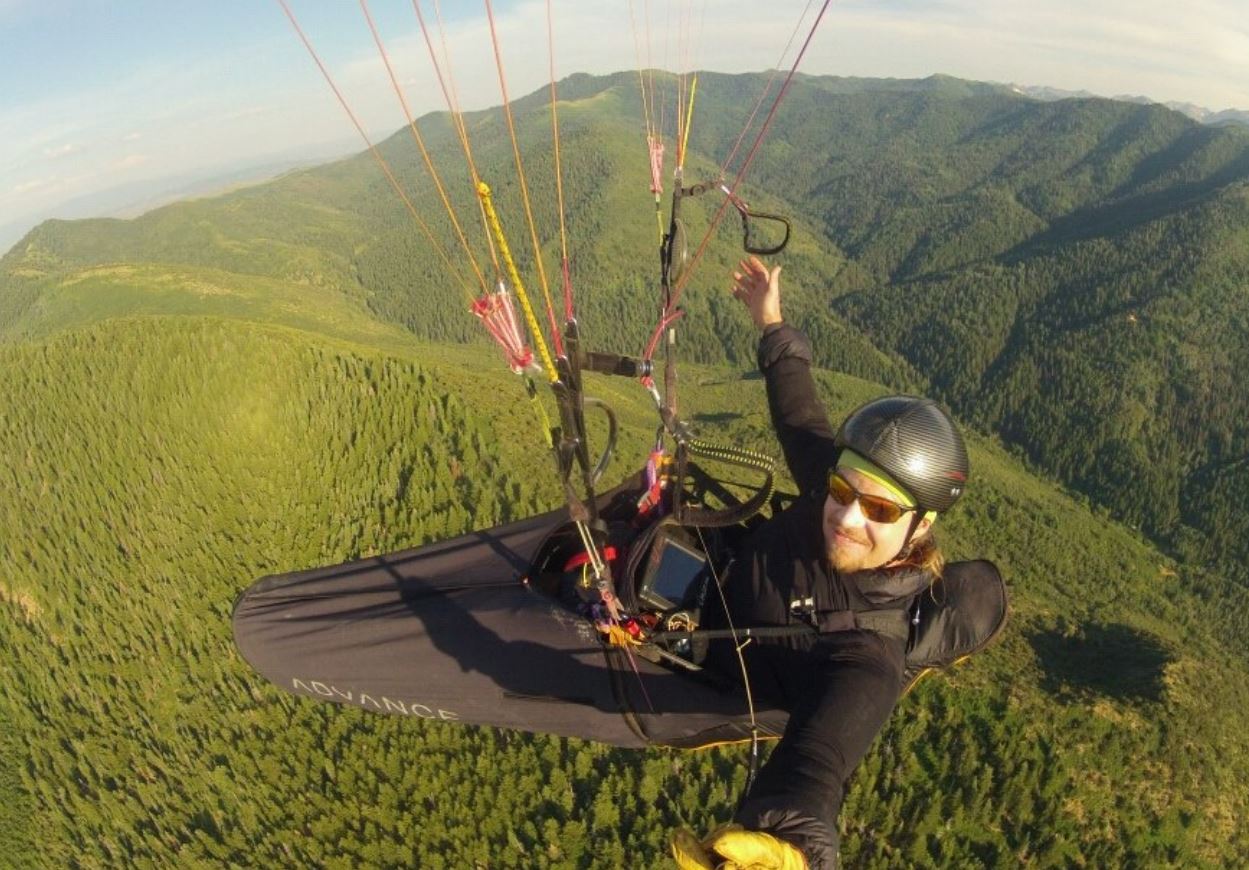 Damien Mitchell paragliding over green mountains